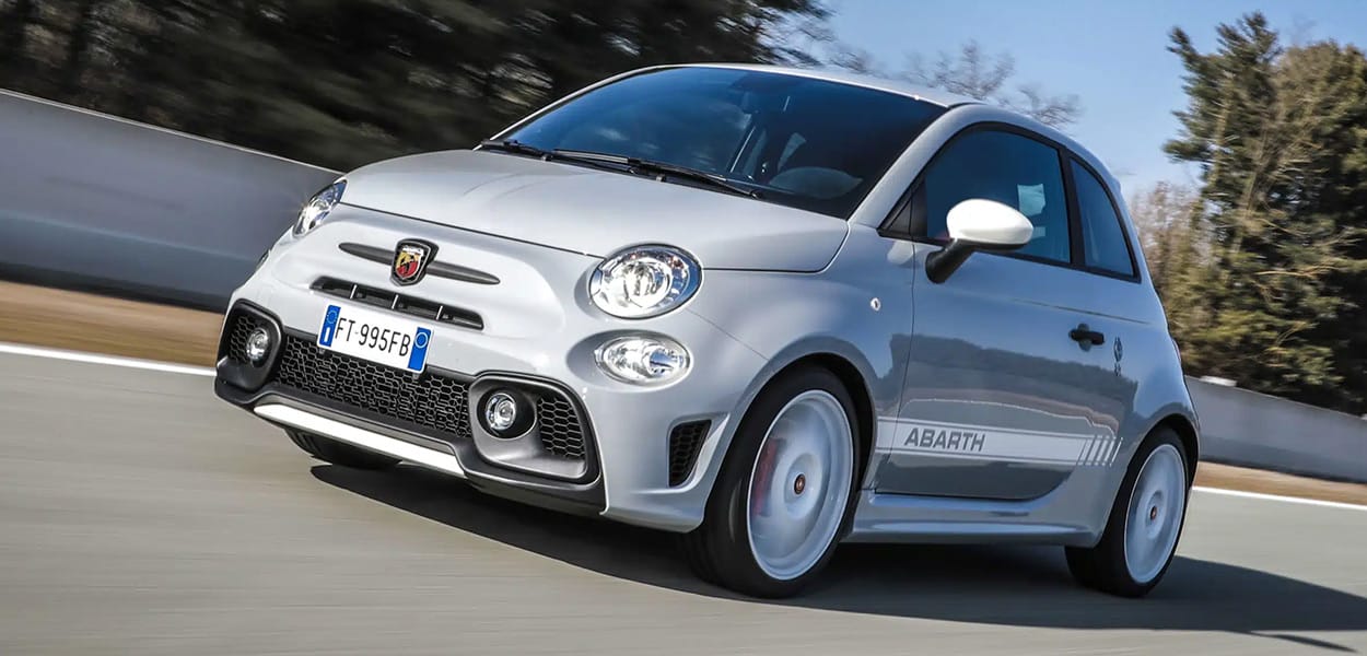 Ein grauer-weißer Abarth 595 Turismo fährt über eine Straße.