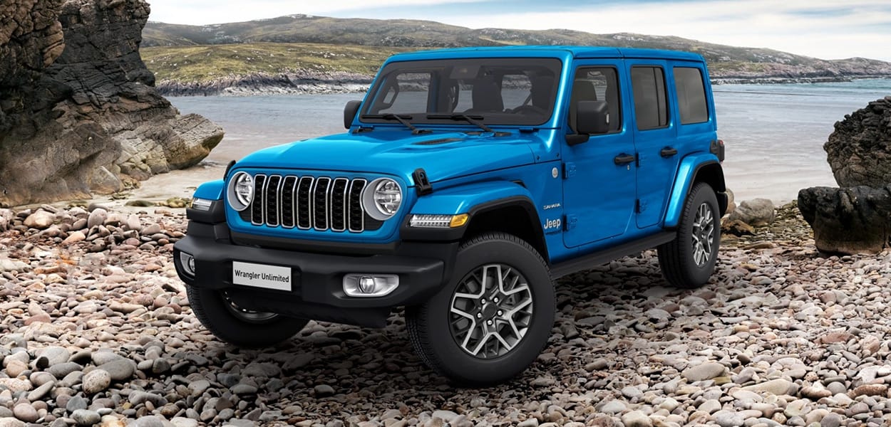 Ein blauer Jeep Wrangler steht an einer steinigen Küste am Meer.