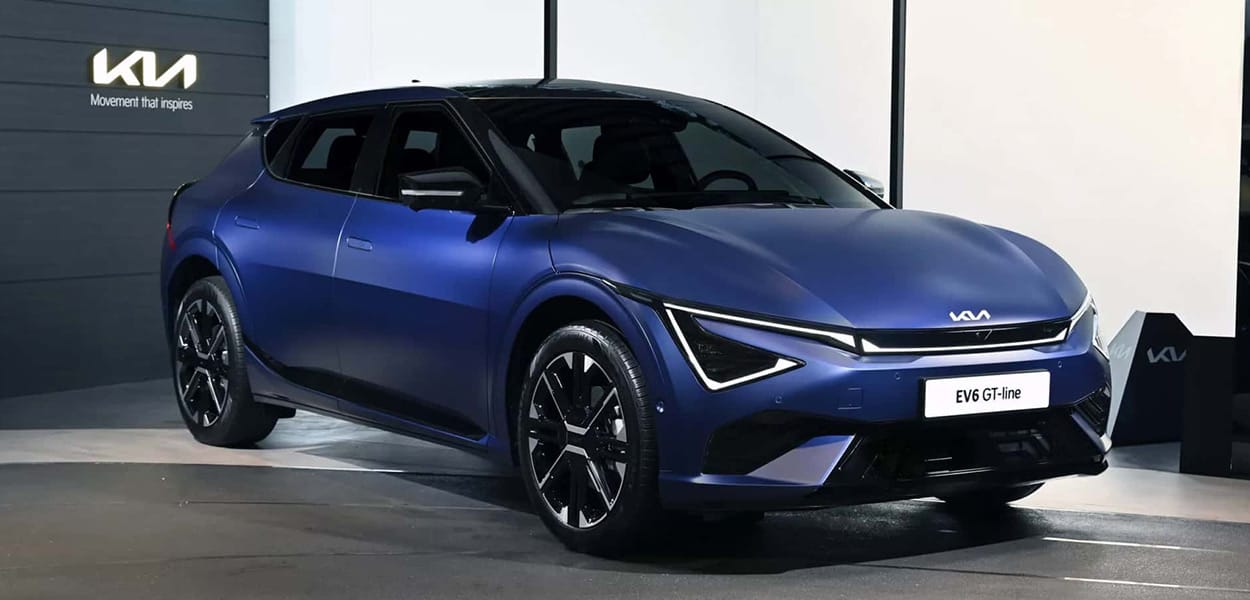 Ein dunkelblauer Kia EV6 steht in einem Showroom vor einer Wand mit dem beleuchteten Kia Logo. 