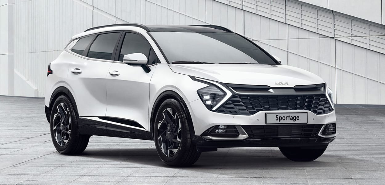 Ein weißer Kia Sportage steht auf einem Platz vor einem modernen Gebäude.