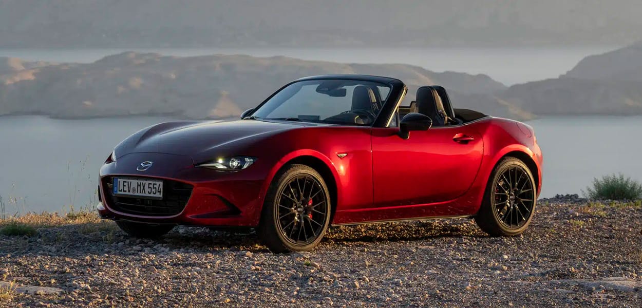 Ein roter Mazda MX-5 Cabrio steht auf einem Weg am Meer.