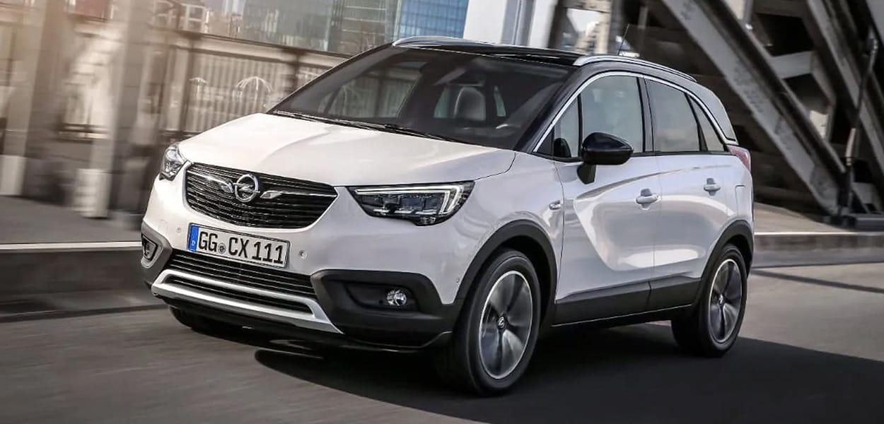 Ein weißer Opel Crossland mit einem schwarzen Dach fährt über eine Brücke.