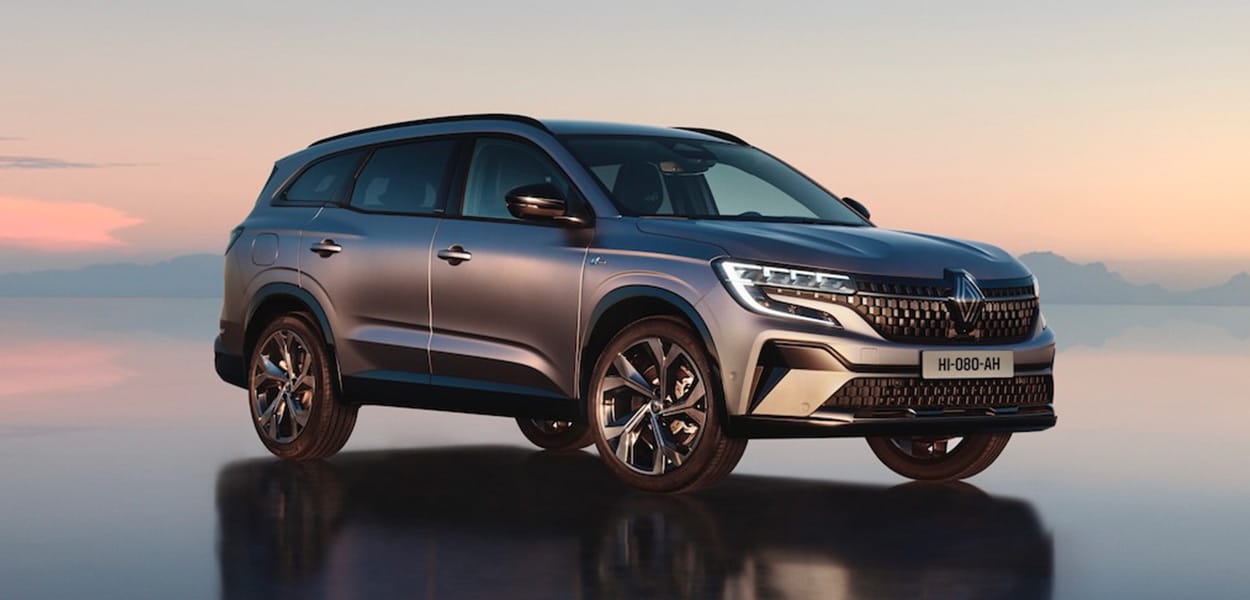 Ein silbergrauer Renault Espace steht auf einer gespiegelten Fläche vor einer Bergkulisse.