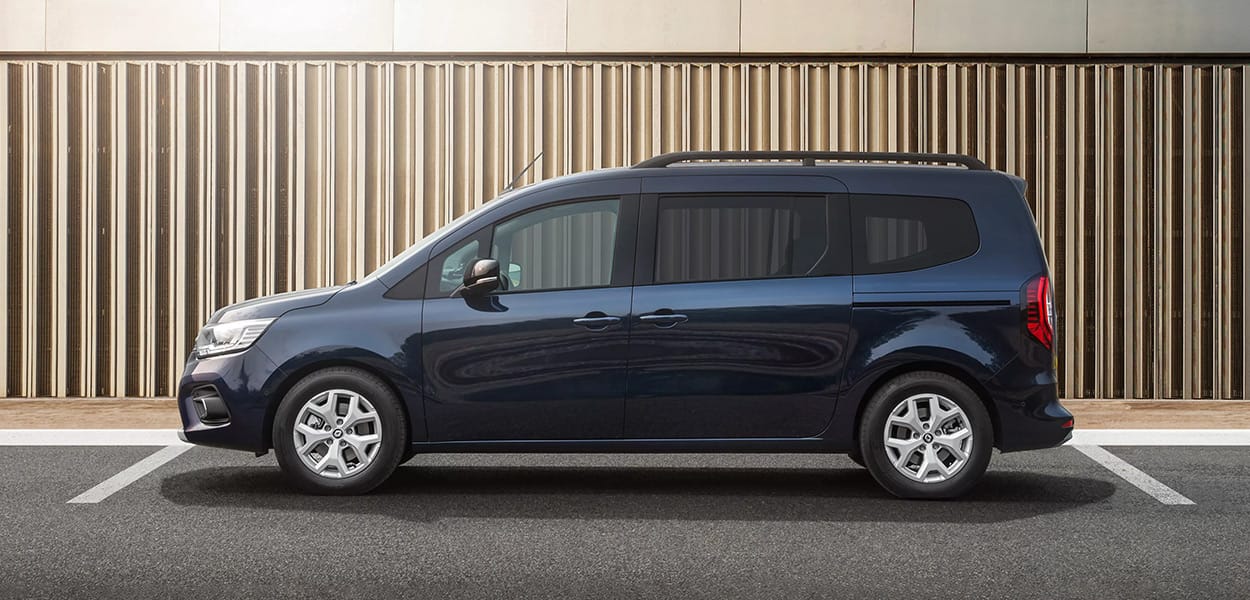 Seitenansicht von einem dunkelblauen Renault Kangoo Van auf einem Parkplatz vor ein modernen Gebäude.