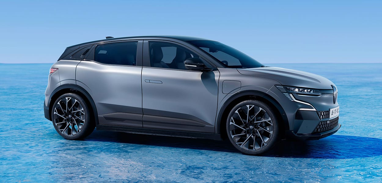 Ein grauer Renault Megane E-Tech parkt in Szene gesetzt vor einem blauen Hintergrund.