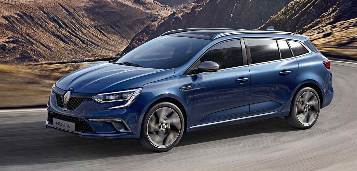 Ein blauer Renault Megane fährt um eine Kurve in einer Berglandschaft.