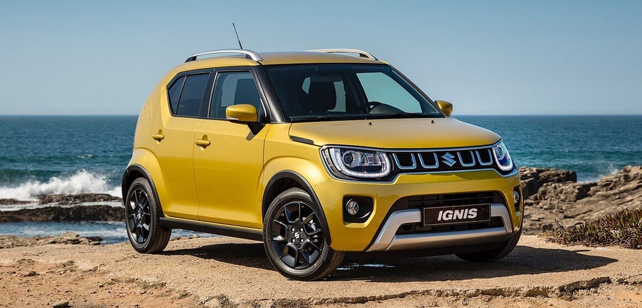 Ein gelber Suzuki Ignis steht auf einem felsigen Platz am Meer.