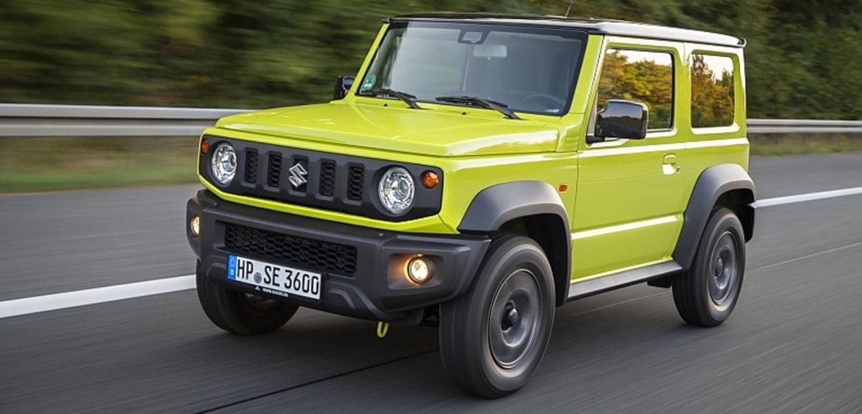 Grüner Suzuki Jimny Geländewagen auf einer Landstraße in Fahrt – kompakter Offroader mit markantem Design und hoher Geländetauglichkeit.
