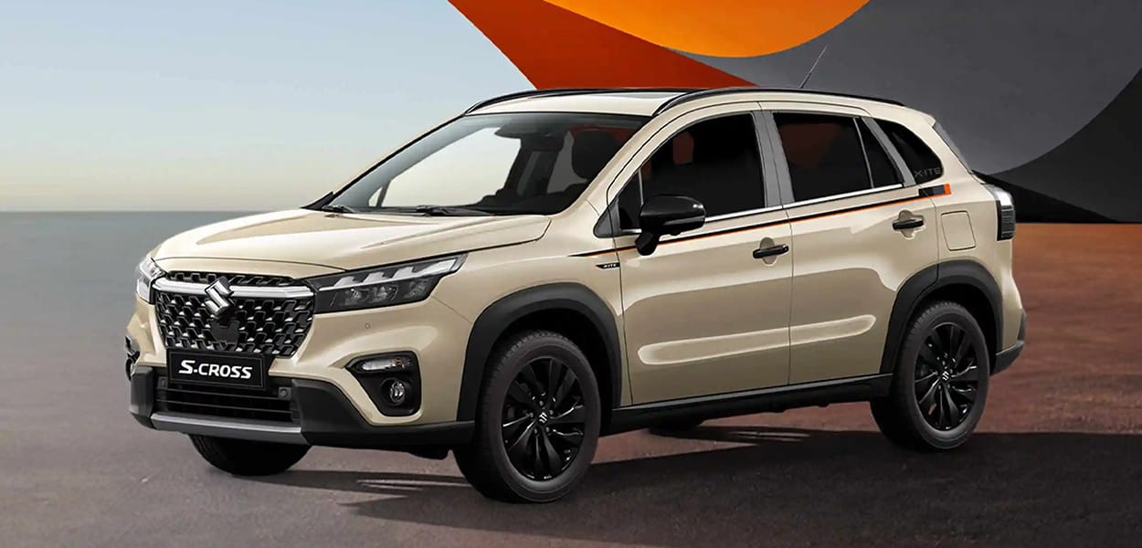Ein beiger Suzuki SX4 S-Cross parkt auf einem Platz vor einem bunten, modernen Gebäude.